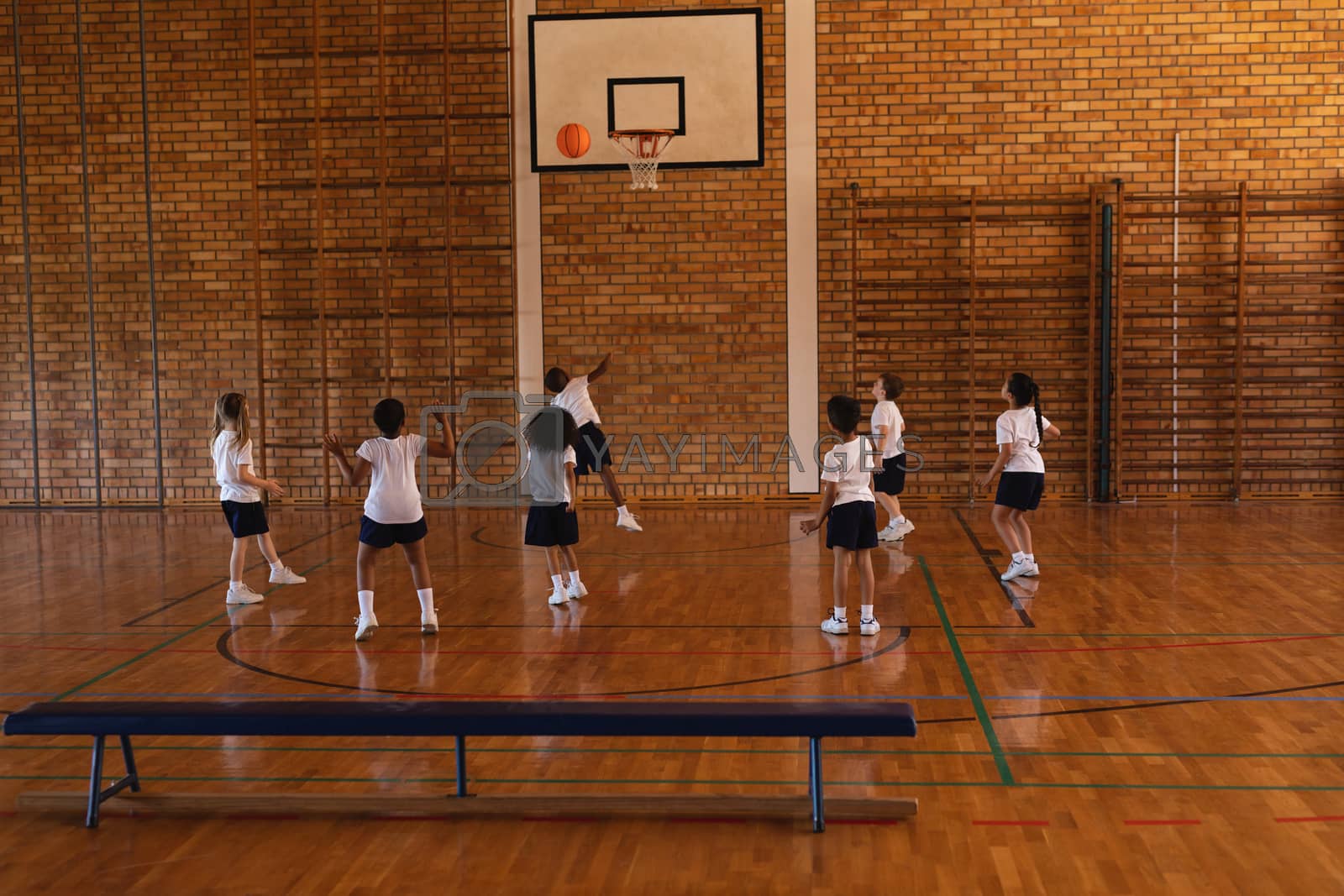Royalty free image of Schoolkids playing basketball at basketball court by Wavebreakmedia
