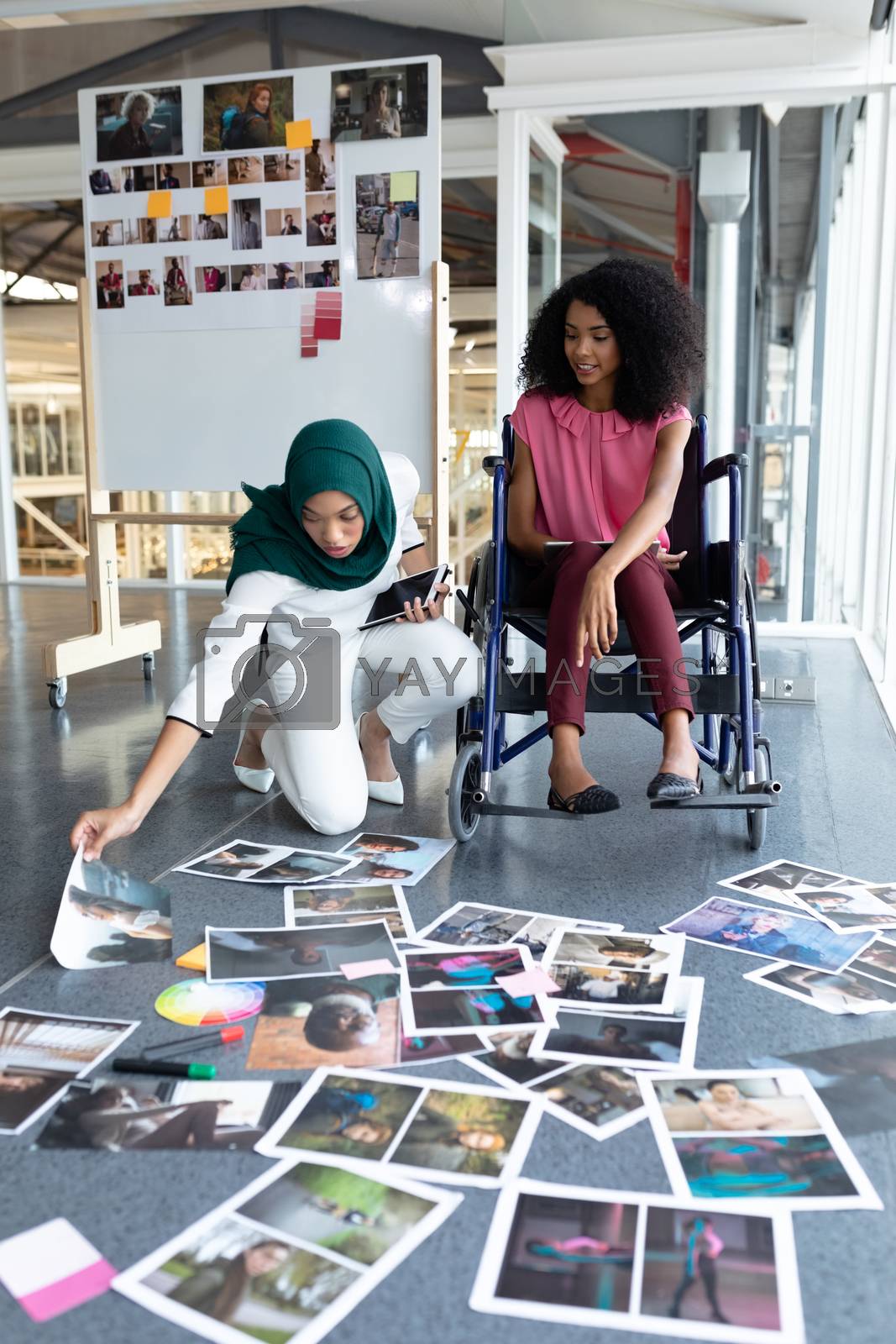 Royalty free image of Female graphic designers looking at photographs in office by Wavebreakmedia