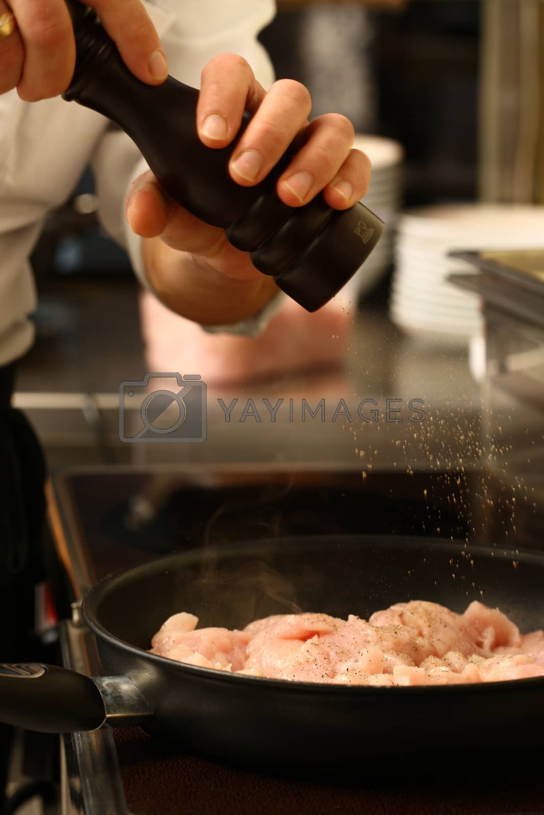 Royalty free image of professional cook in kitchen preparing food for customers showing by PeterHofstetter