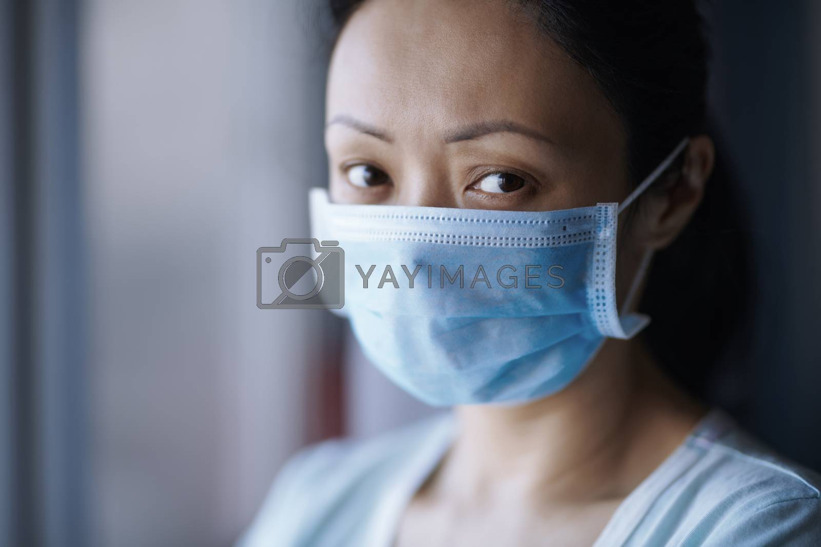 Royalty free image of Woman staying at home wearing protective surgical mask by Novic