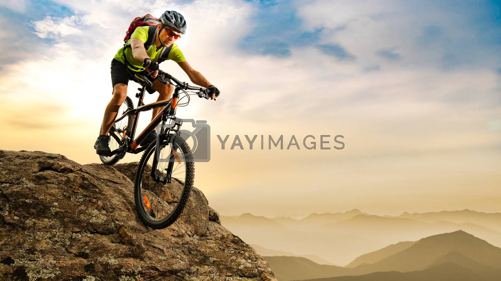 Royalty free image of Cyclist Riding the Bike Down the Rock at Sunrise in the Mountains. Extreme Sport and Enduro Biking Concept. by maxpro