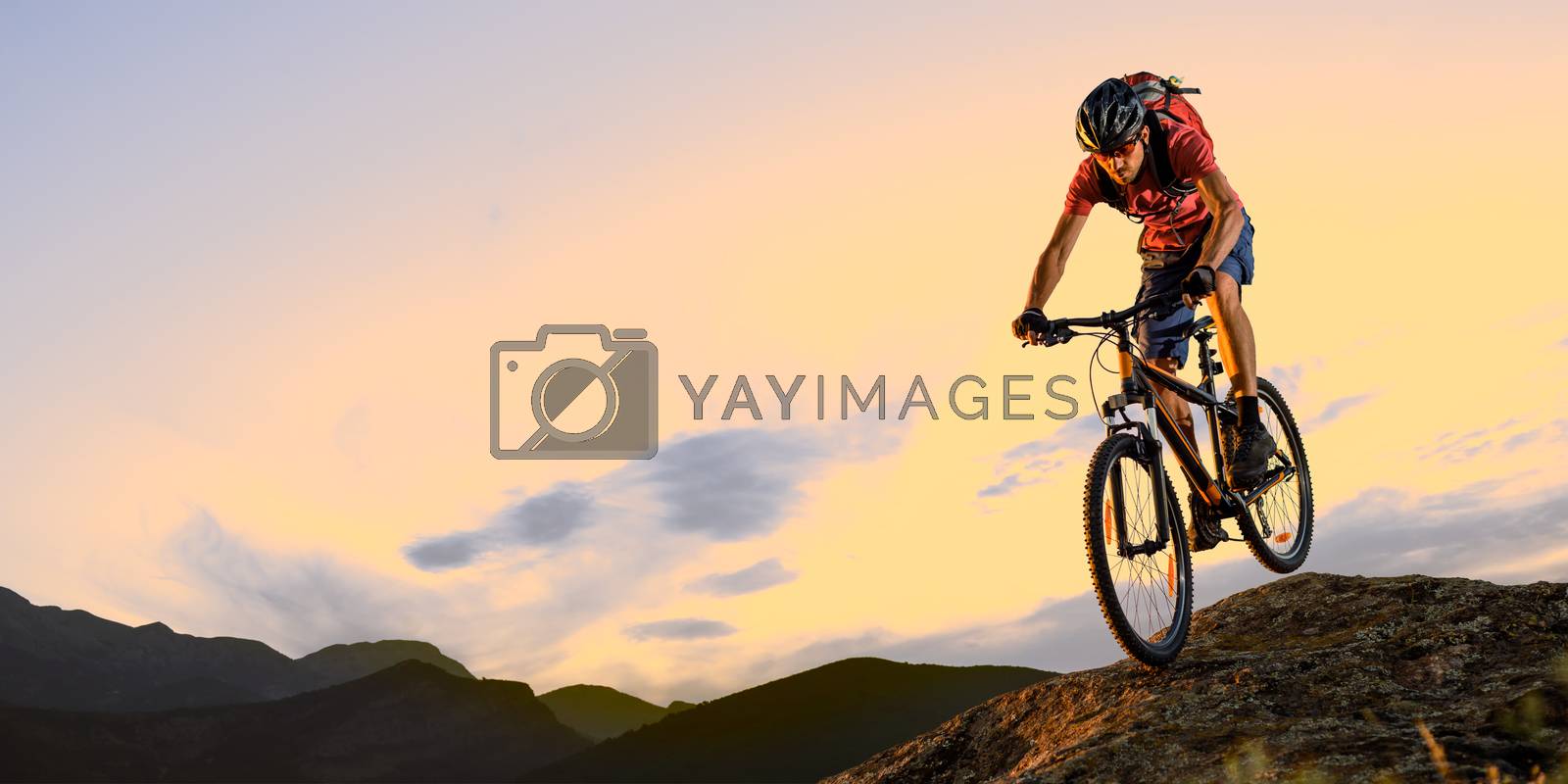 Royalty free image of Cyclist in Red Riding the Bike Down the Rock at Sunset. Extreme Sport and Enduro Biking Concept. by maxpro