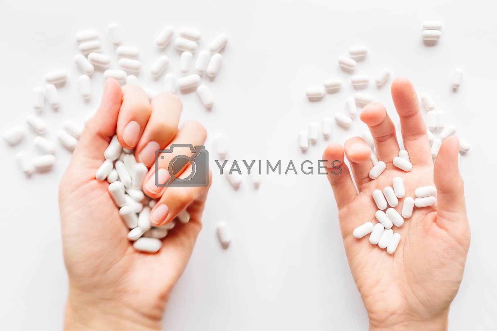 Royalty free image of Palm hands full of white scattering pills. Woman gripes hand wit by aksenovko