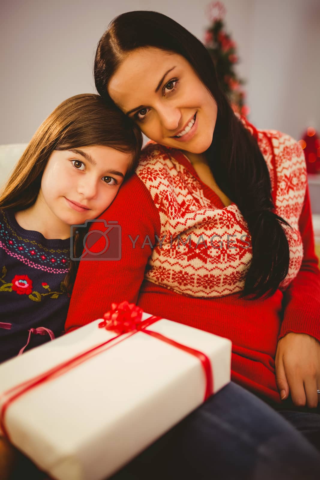 Royalty free image of Festive mother and daughter holding christmas present by Wavebreakmedia