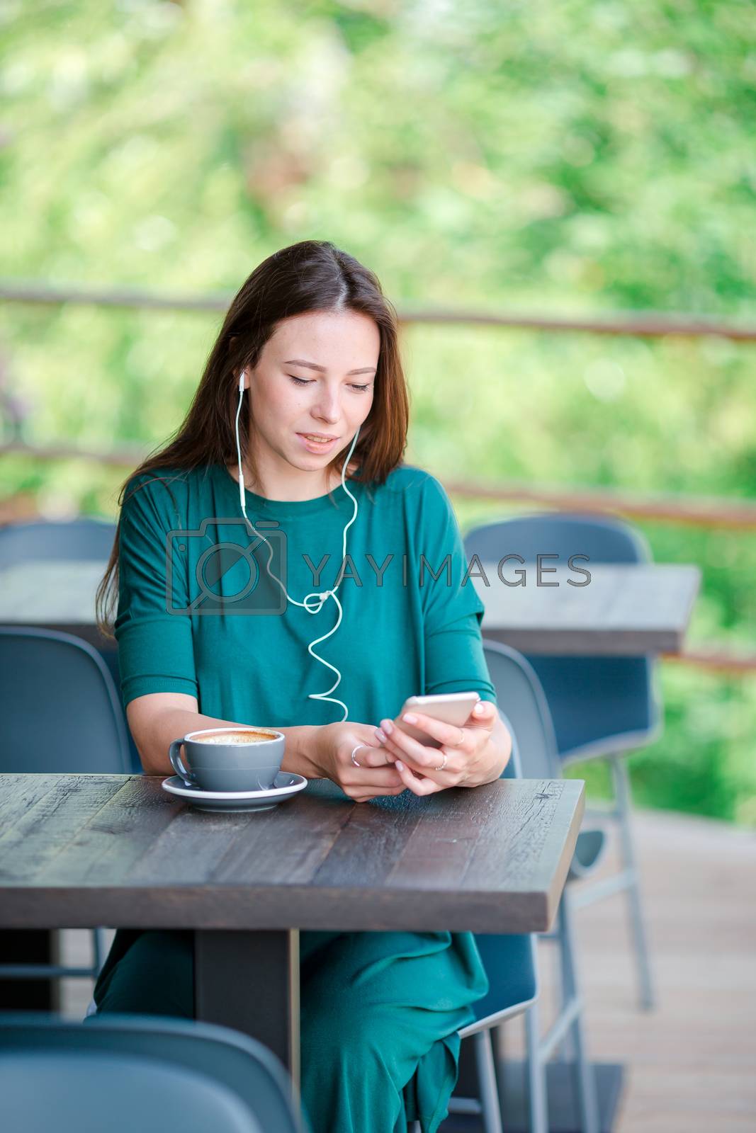 Royalty free image of Young woman with smart phone while sitting alone in coffee shop during free time by travnikovstudio