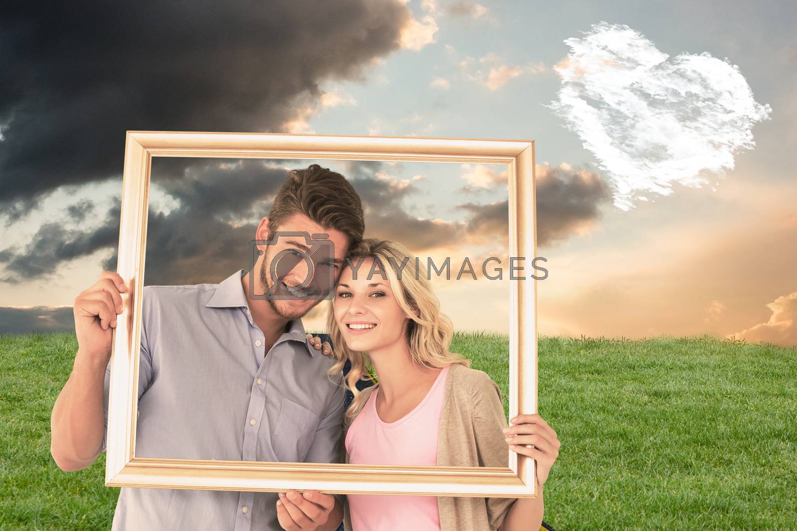 Royalty free image of Composite image of attractive young couple holding picture frame by Wavebreakmedia