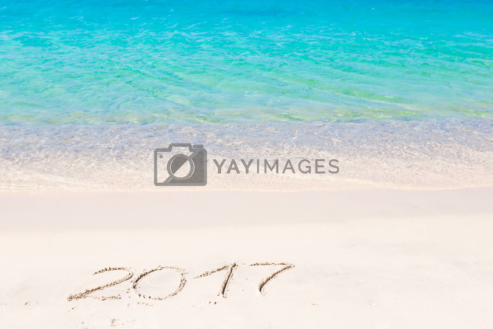 Royalty free image of 2017 handwritten on sandy beach with soft ocean wave on background by travnikovstudio