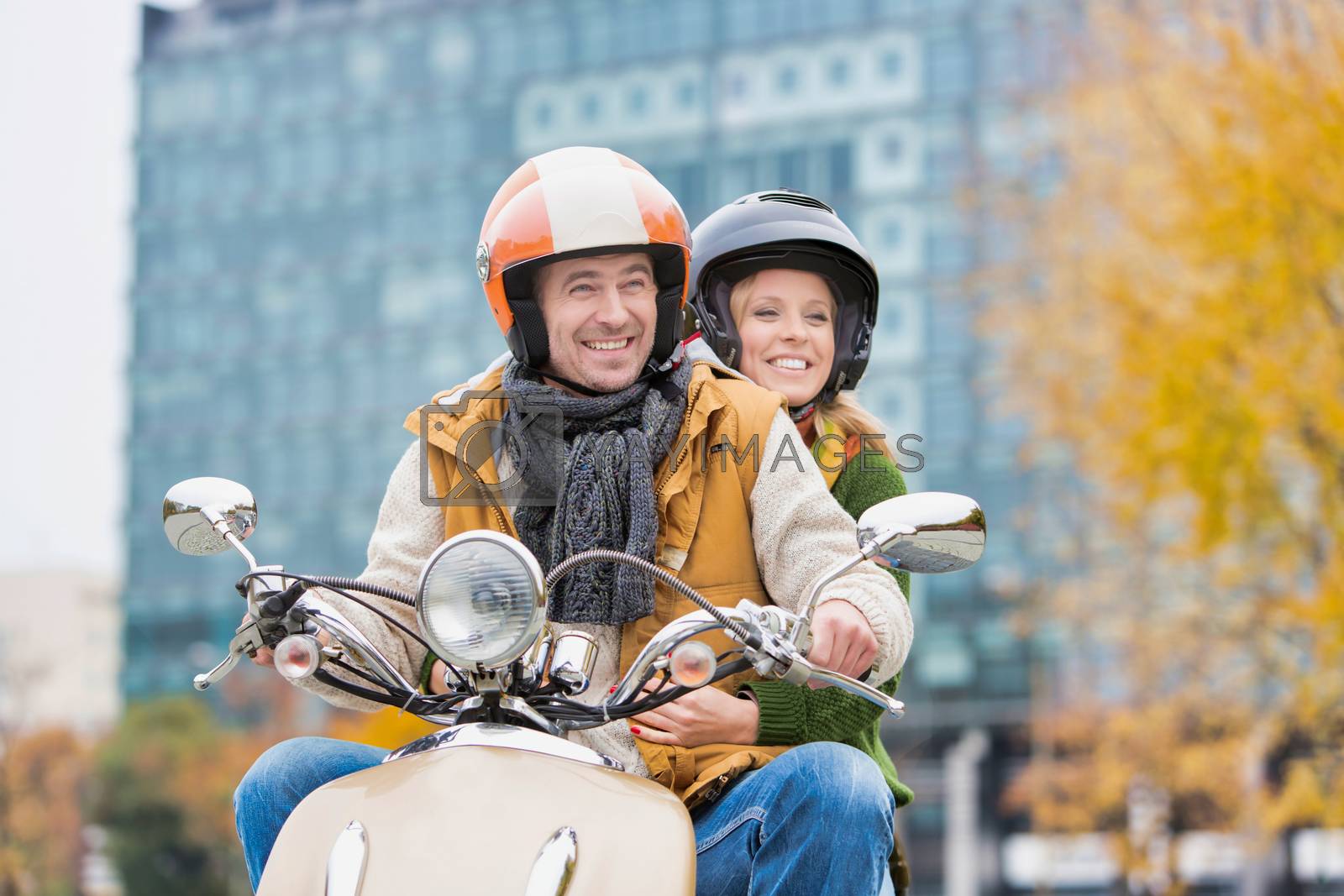 Royalty free image of Portrait of mature man driving motorbike with his wife in park by moodboard