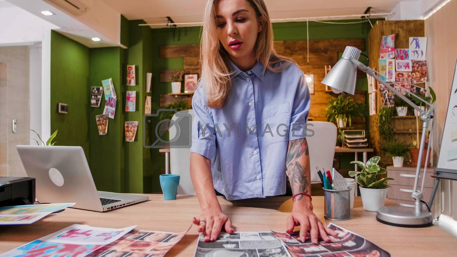 Royalty free image of Young designer looking at some prints to choose the best one by DCStudio
