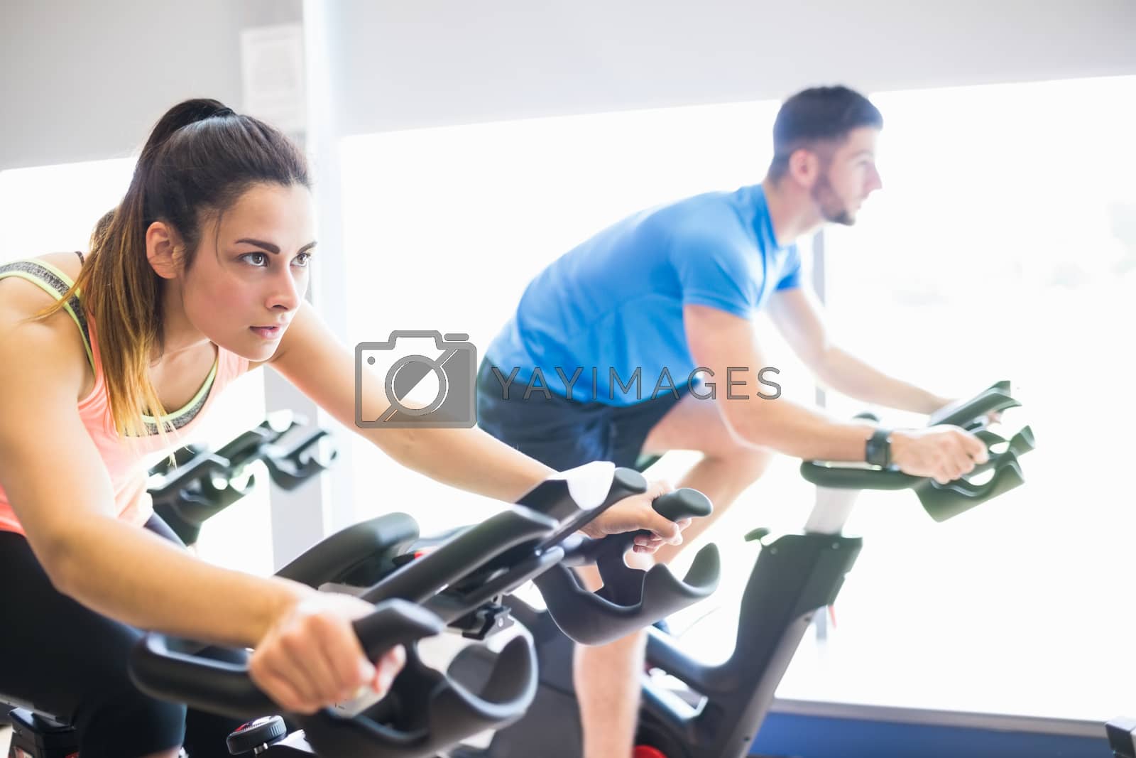 Royalty free image of Man and woman using cycling exercise bikes by Wavebreakmedia