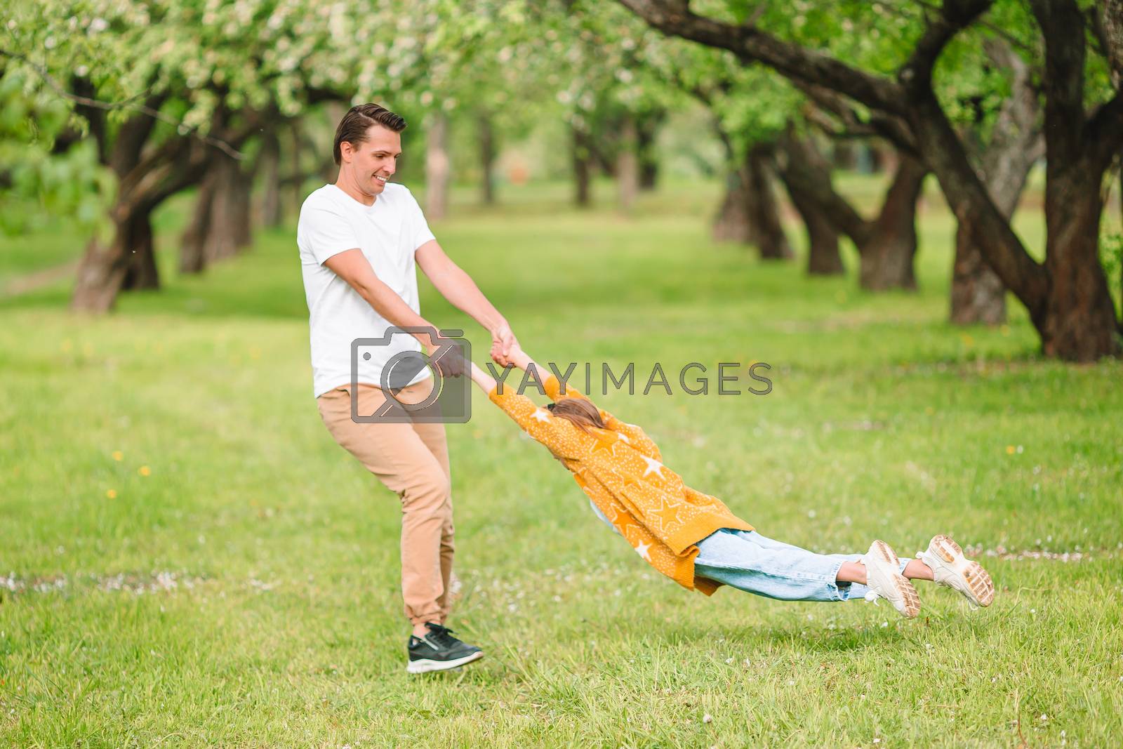Royalty free image of Family of father and daughter in blooming cherry garden by travnikovstudio