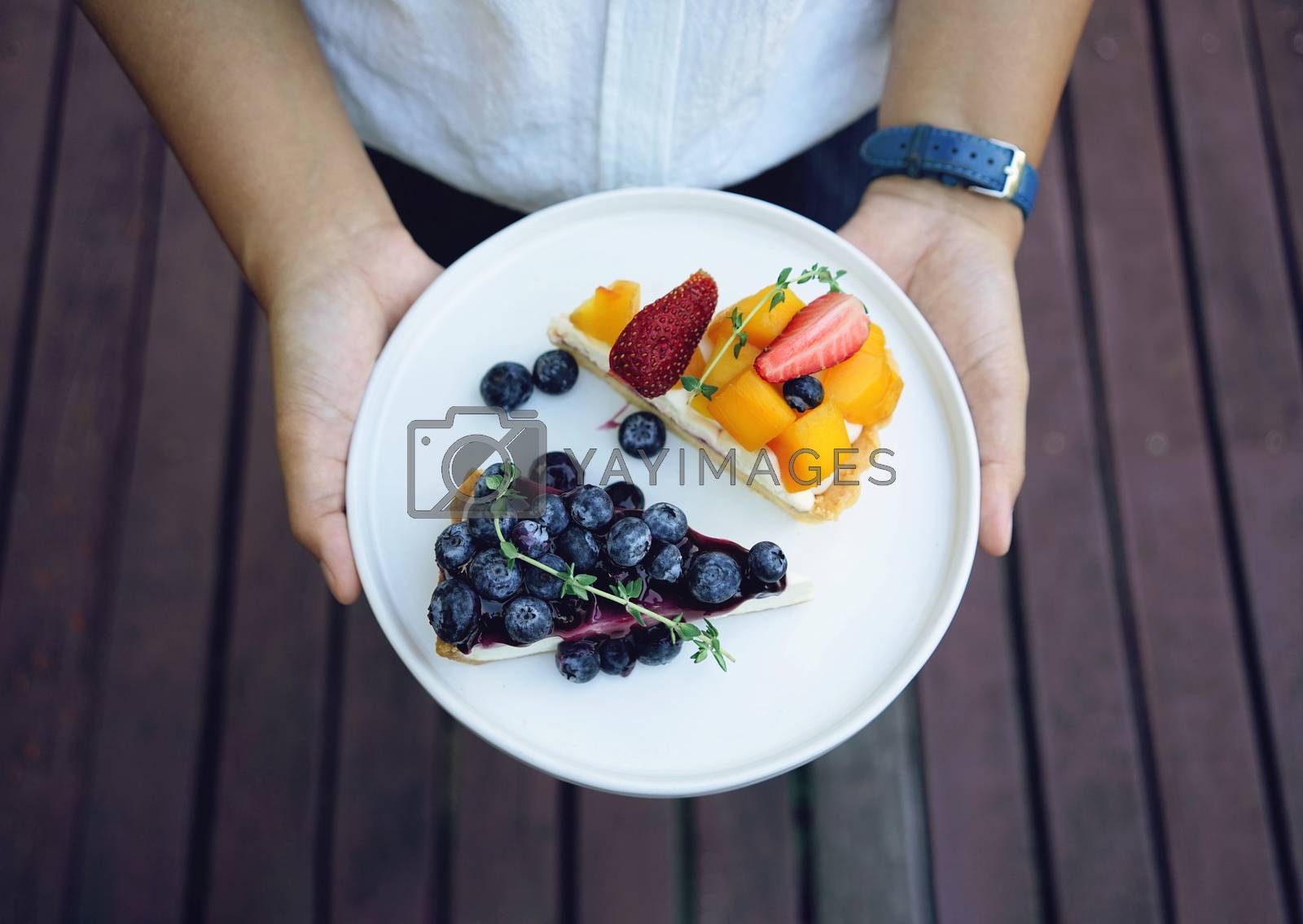 Royalty free image of Close up woman hands holding plate of blueberry pie and mango wi by nuchylee