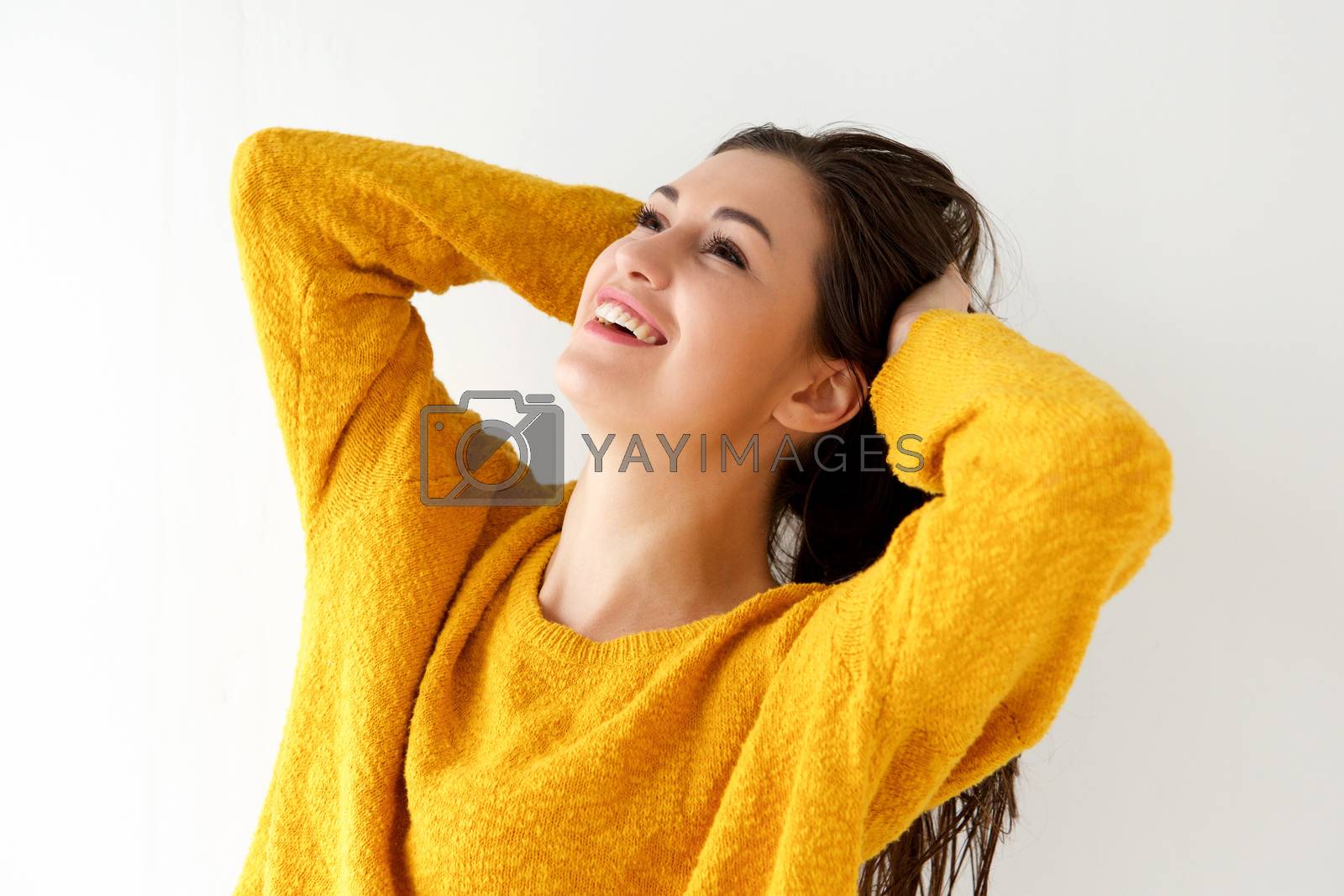 Royalty free image of Close up smiling young woman with hands behind head and looking up by mimagephotography