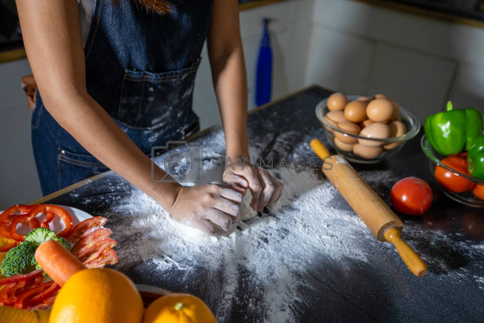 Royalty free image of Asian women preparing a pizza, knead the dough and puts ingredie by Tuiphotoengineer