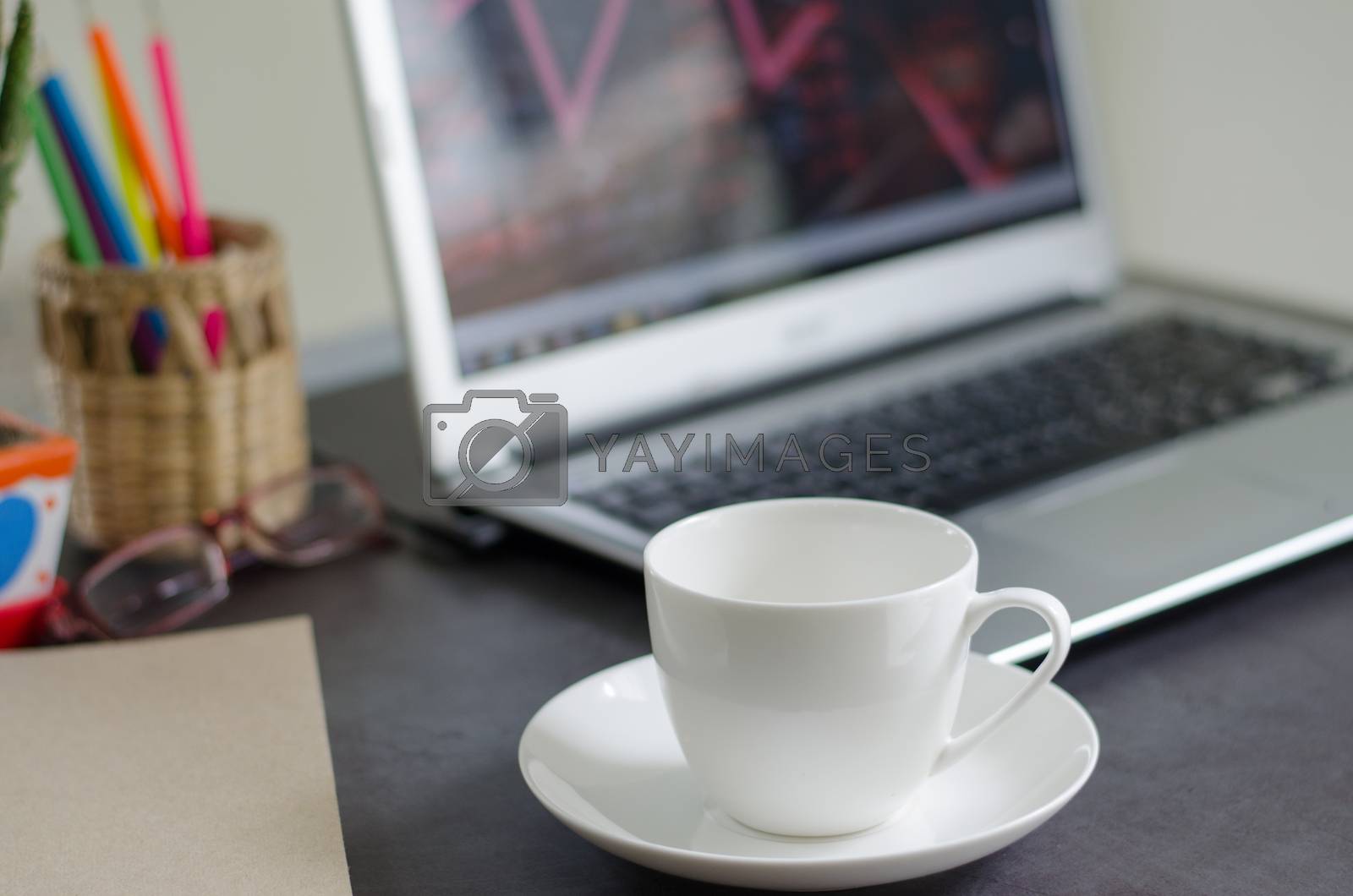 Royalty free image of Coffee mugs and laptops on work desk at home. by kitti