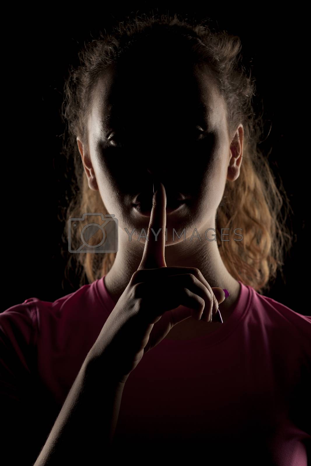 Royalty free image of woman with the face in the shadow holding finger on her lips by Vladimirfloyd