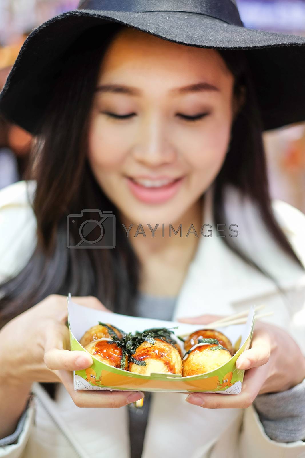 Royalty free image of 
Chinese Asian young female model eating dumpling batter (Takoya by Surasak
