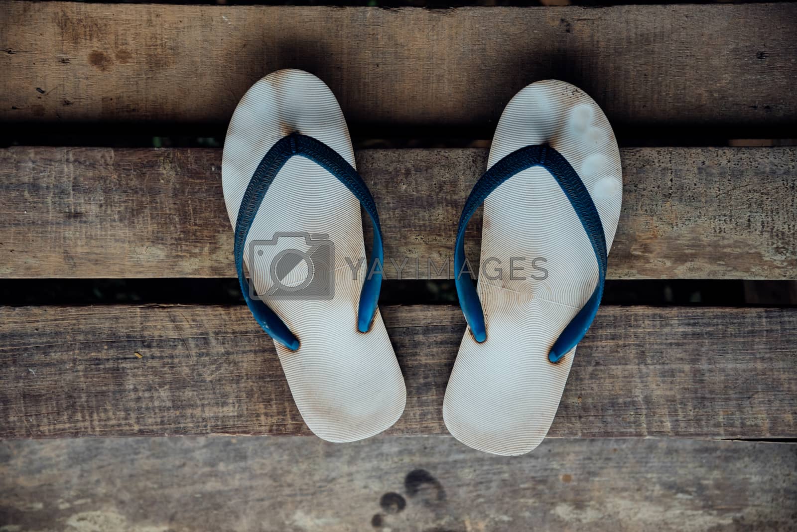 Royalty free image of Sandal or flip-flop blue color on wooden staircase by PongMoji