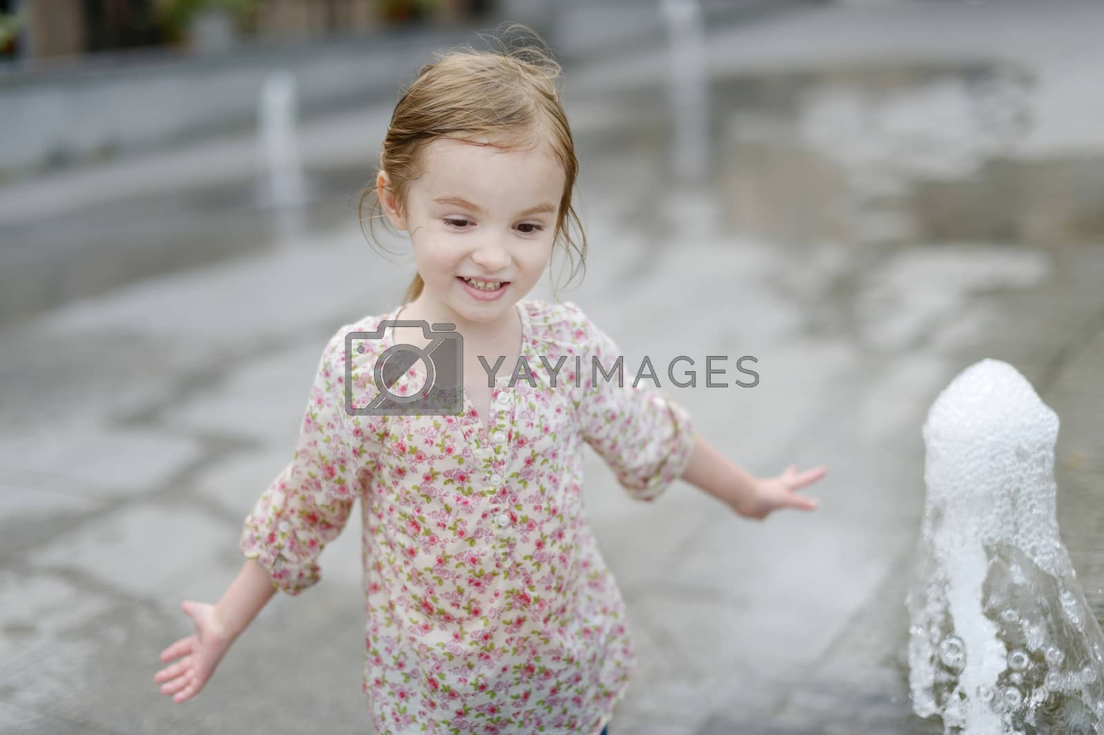 Royalty free image of Adorable little girl having fun by a fountain by maximkabb