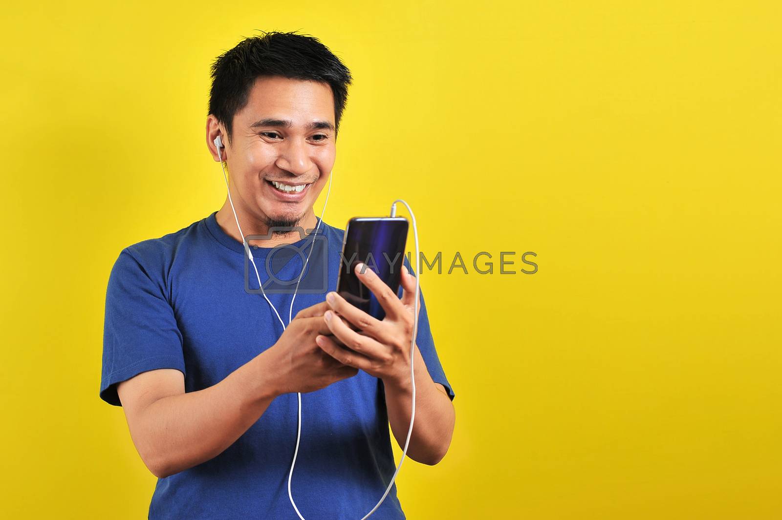 Royalty free image of Portrait of excited Asian man surprised to find a trending song  by heruan1507