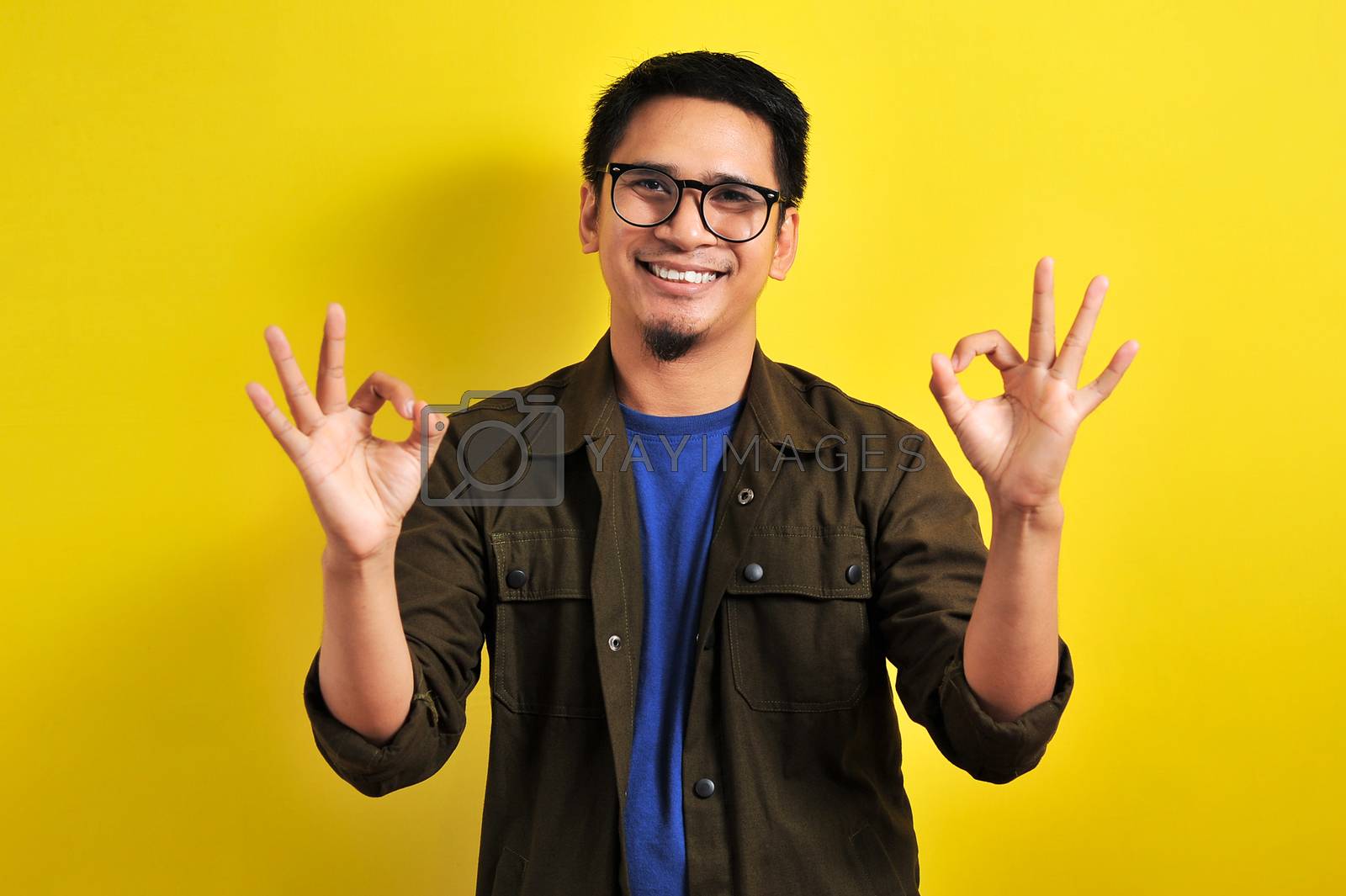 Royalty free image of Indonesian man smiling doing double okay wearing eyeglasses by heruan1507