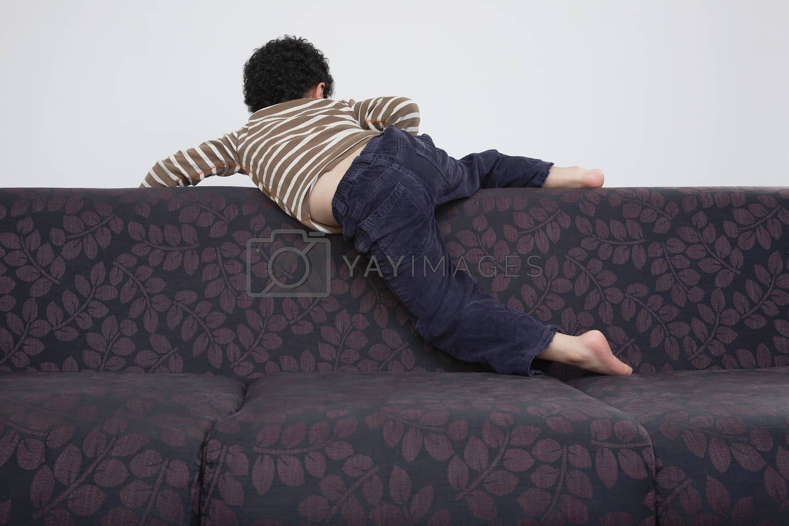 Royalty free image of Boy (5-6) climbing over sofa by moodboard