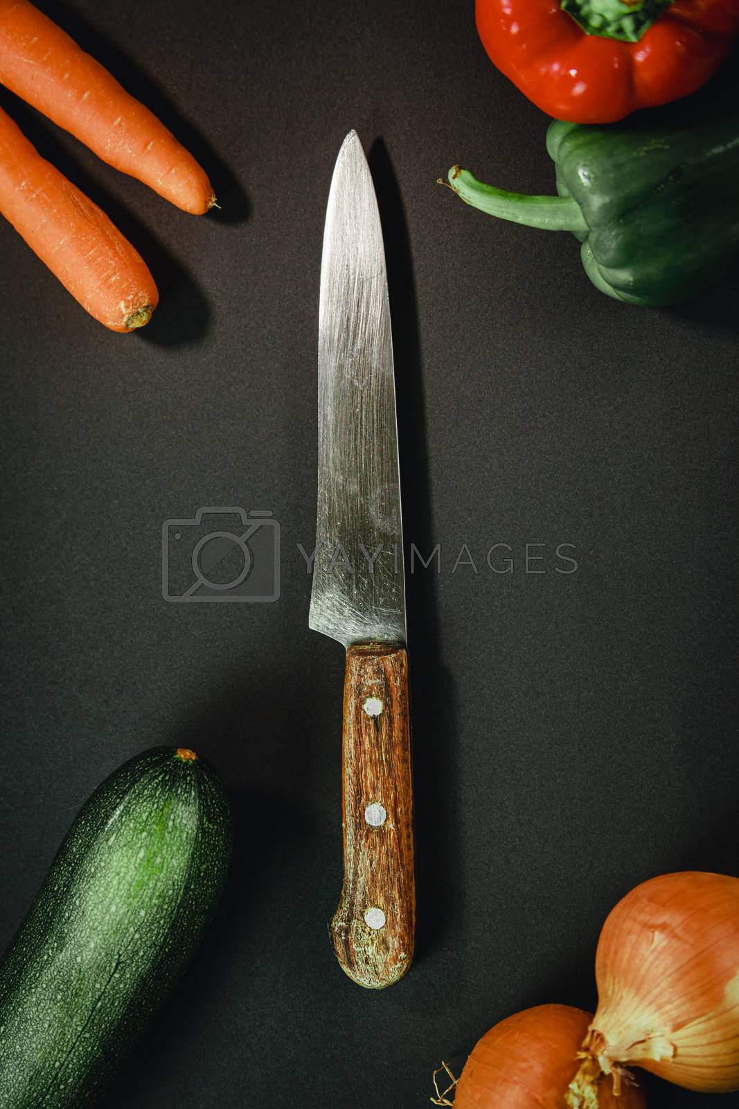 Royalty free image of Long chef knife surrounded by vegetables by AveCalvar