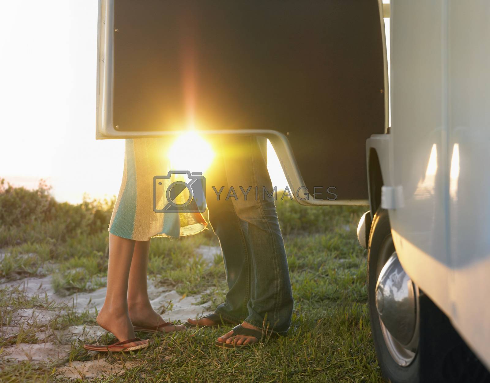 Royalty free image of Young couple face to face beside camper van low section by moodboard