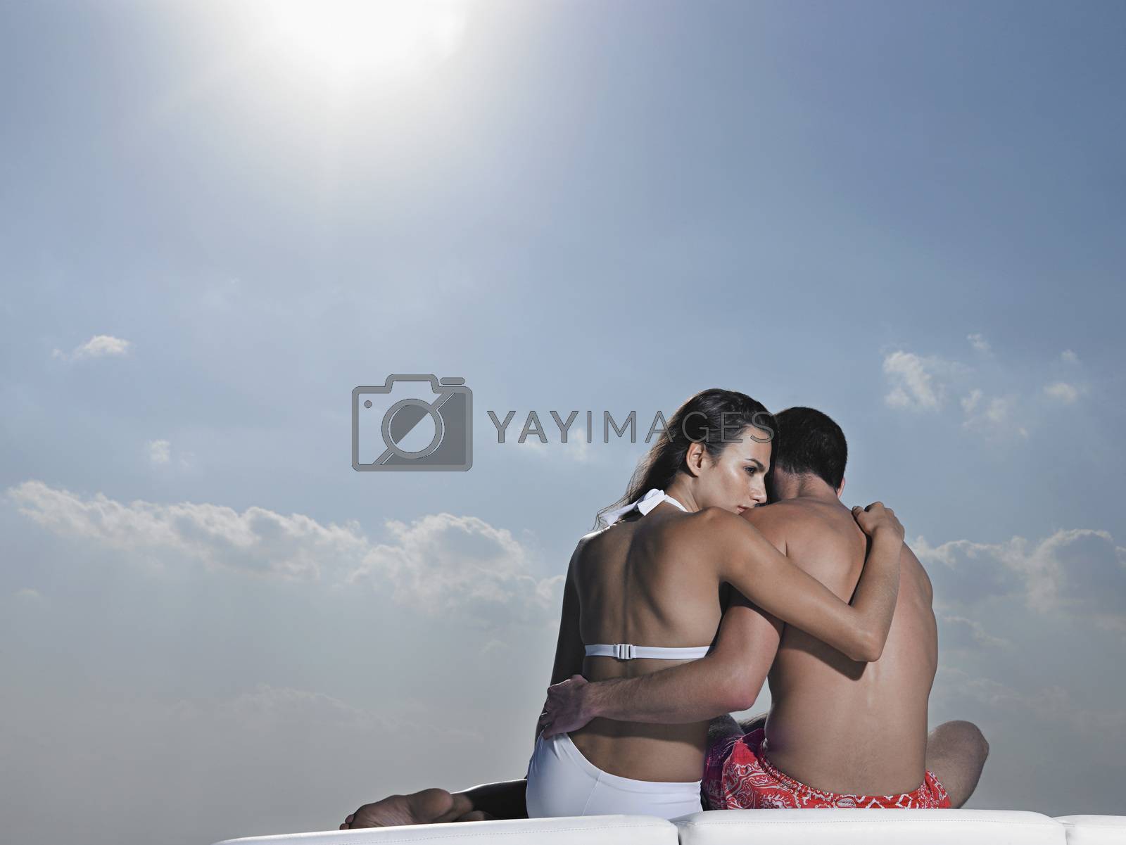 Royalty free image of Young couple embracing on cushions outdoors back view by moodboard