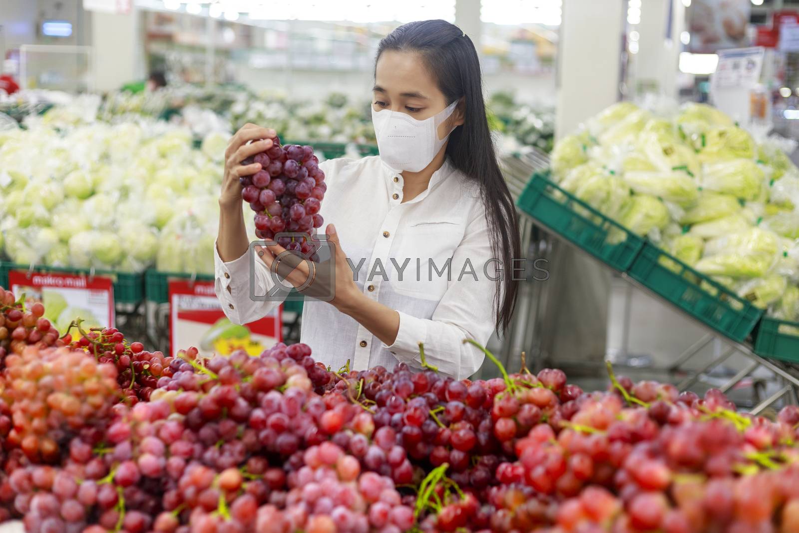 Royalty free image of Asian woman long hair wearing protective face mask  in supermark by Satrinekarn