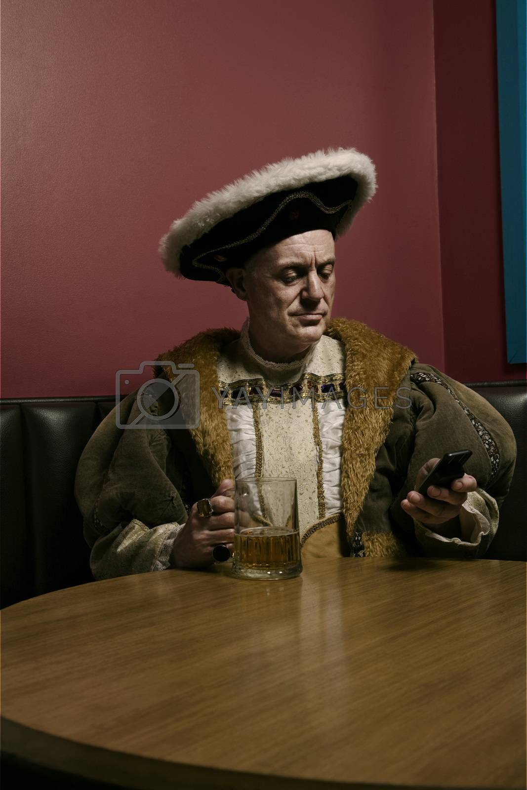Royalty free image of King Henry VIII using mobile phone at table by moodboard