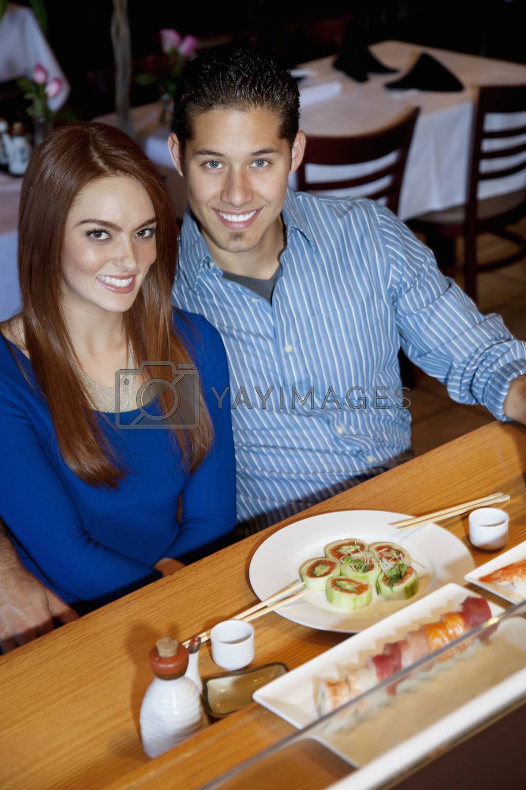 Royalty free image of Portrait of a happy young couple eating Japanese cuisine in restaurant by moodboard
