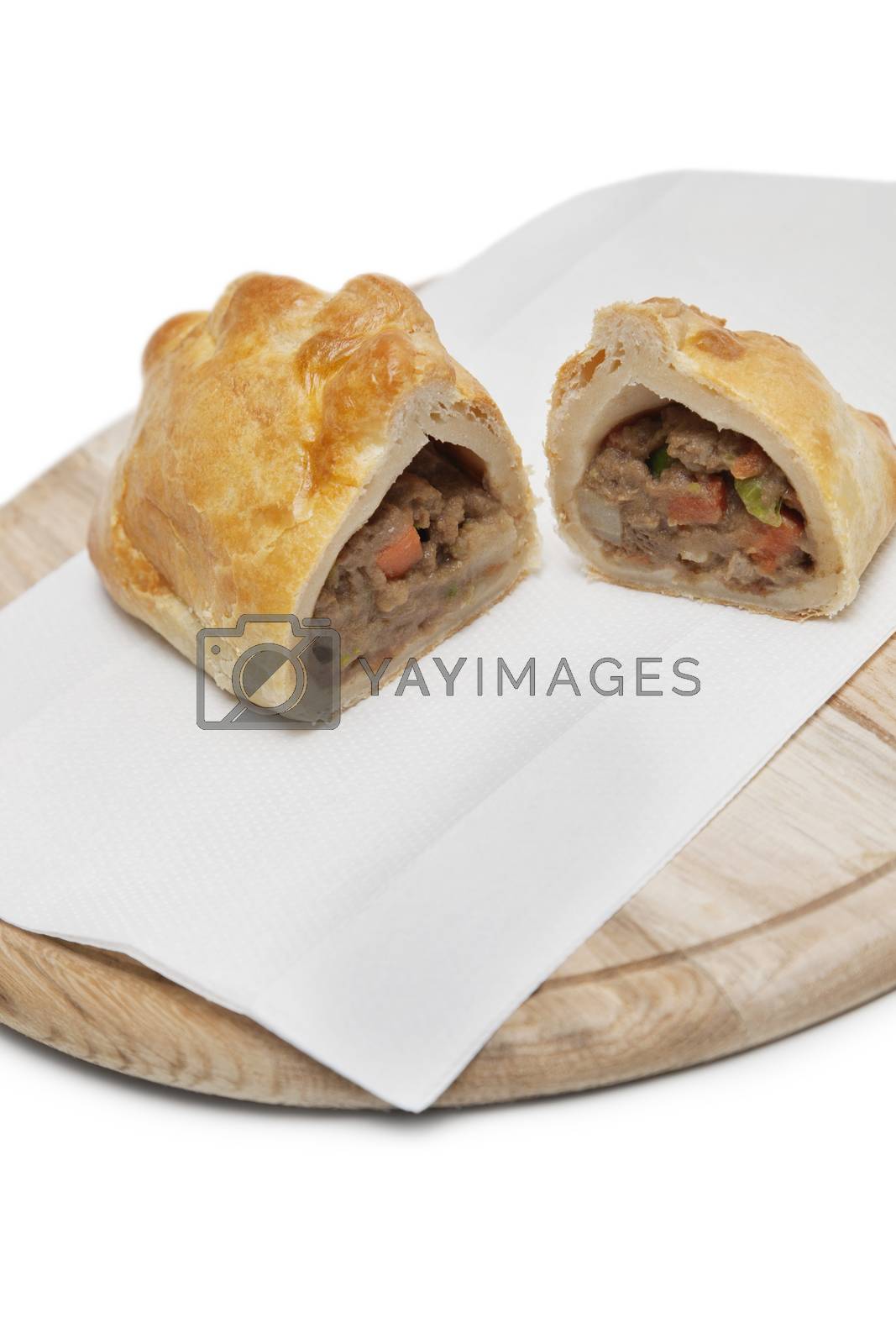 Royalty free image of Two pieces of Cornish pastry and tissue on wooden plate by moodboard