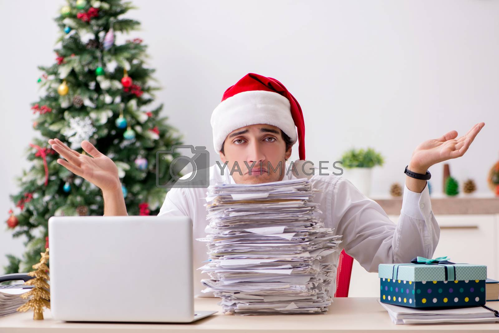 Royalty free image of Young worker working in office on christmas shift by Elnur
