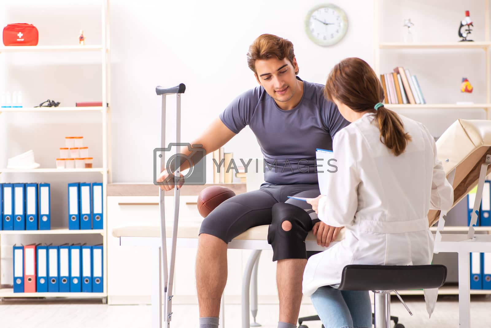 Royalty free image of Handsome american footbal player visiting female doctor traumato by Elnur
