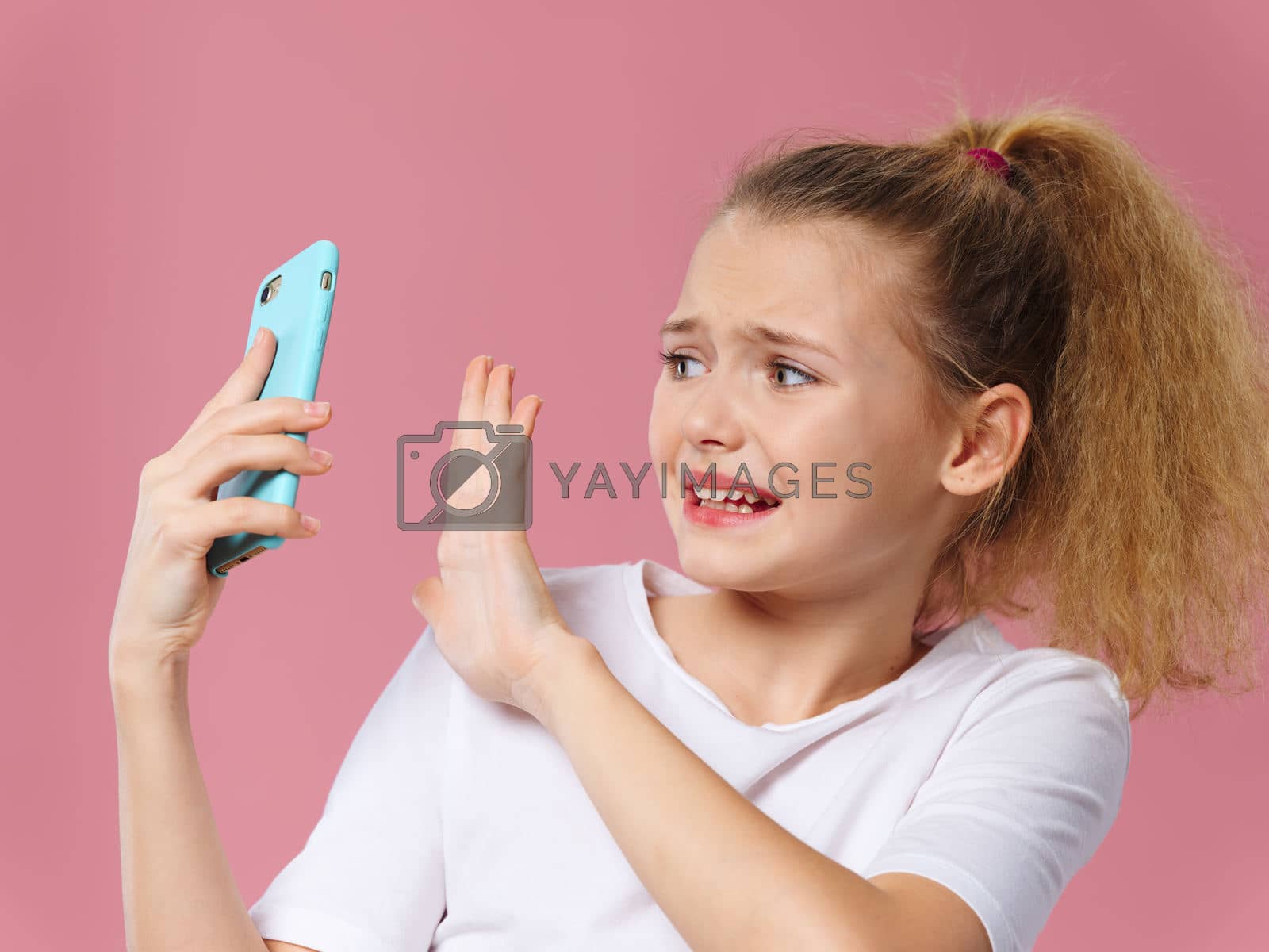 Girl with phone in hands technology communication emotions pink background dissatisfaction