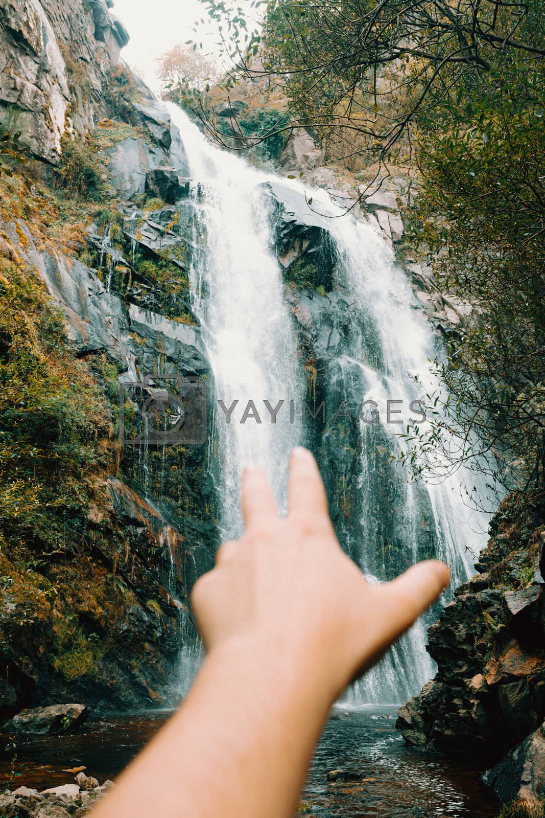 Royalty free image of Out of focus hand reaching to a majestic waterfall by AveCalvar
