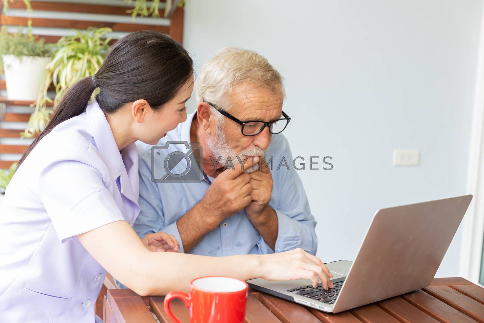 Royalty free image of Nurse help senior retirement man working with laptop at home and by pinkblue