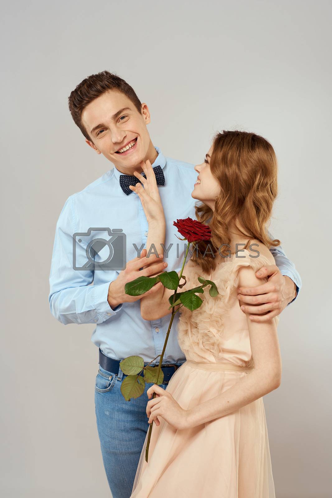 Young couple romance hug relationship dating red rose light studio background. High quality photo