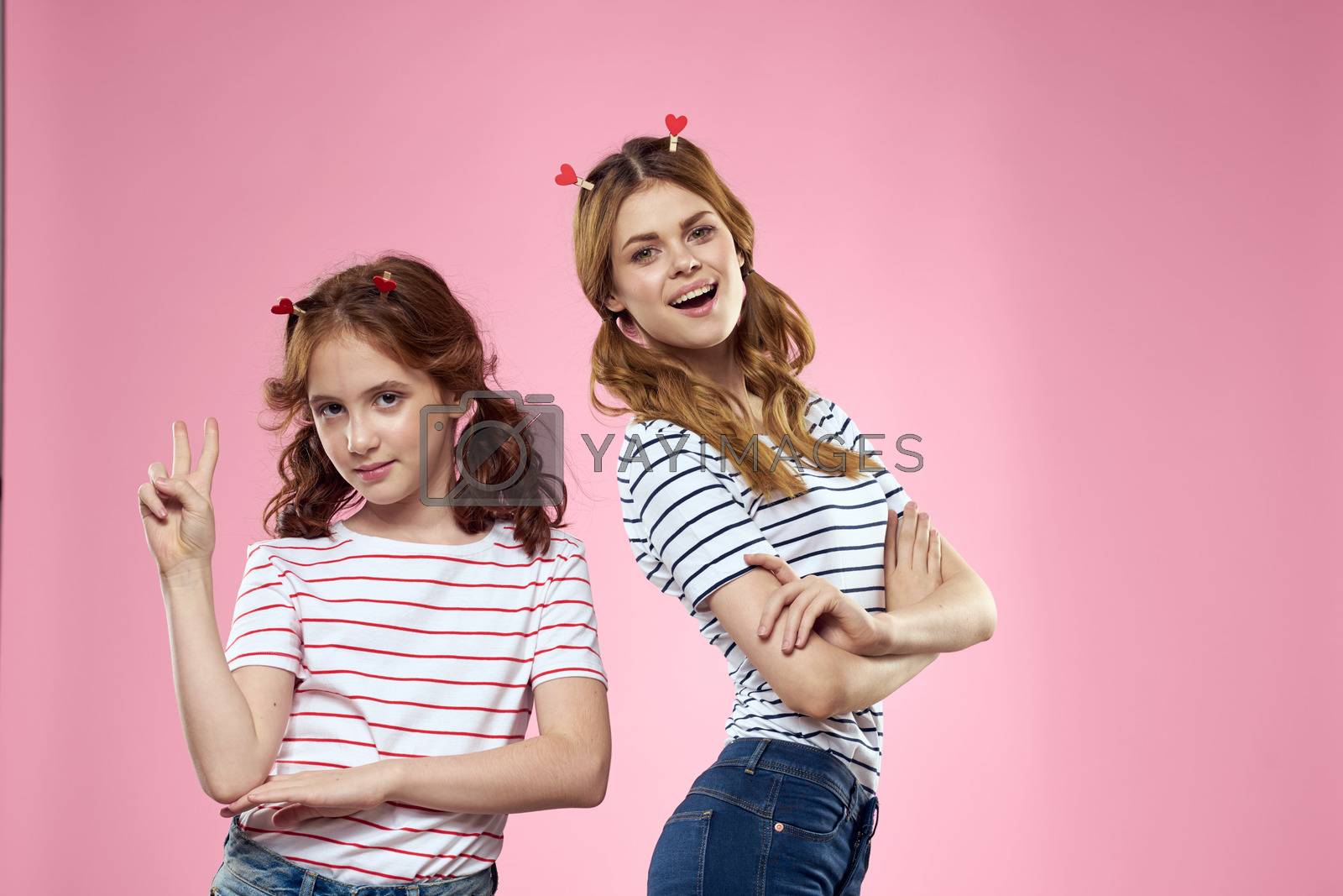 Cheerful mom and daughter lifestyle joy striped shirts family pink background. High quality photo