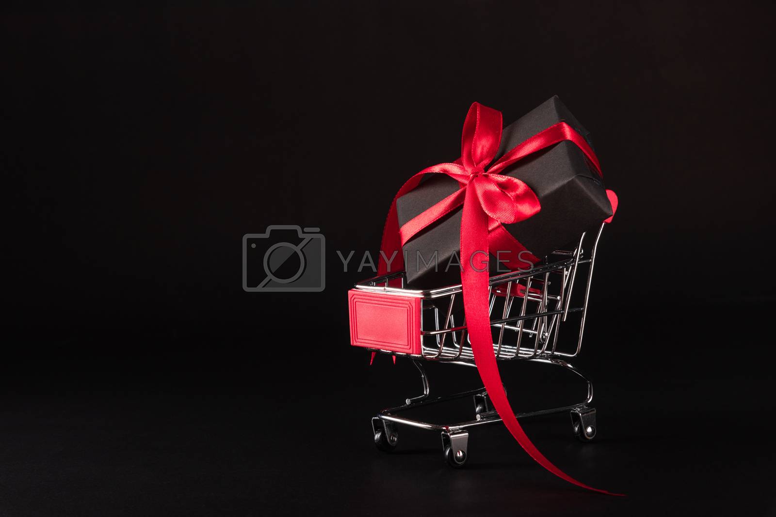 Royalty free image of Gift box wrapped black paper and red bow ribbon present by Sorapop