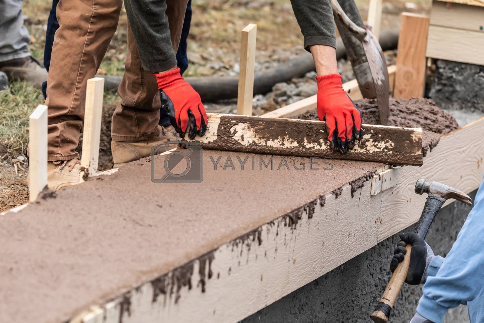 Royalty free image of Construction Worker Leveling Wet Cement Into Wood Framing by Feverpitched