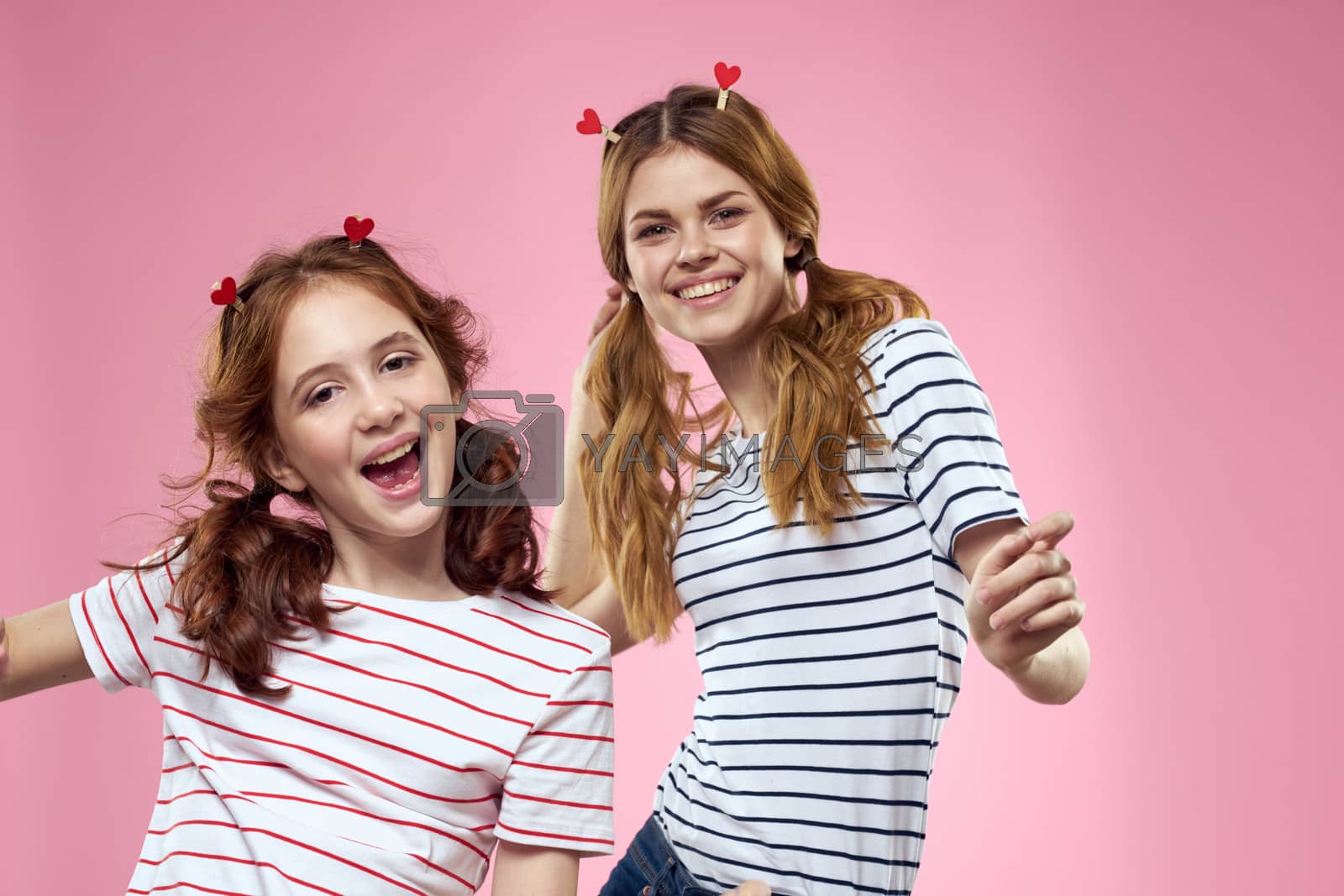 Cheerful mom and daughter lifestyle joy striped shirts family pink background. High quality photo