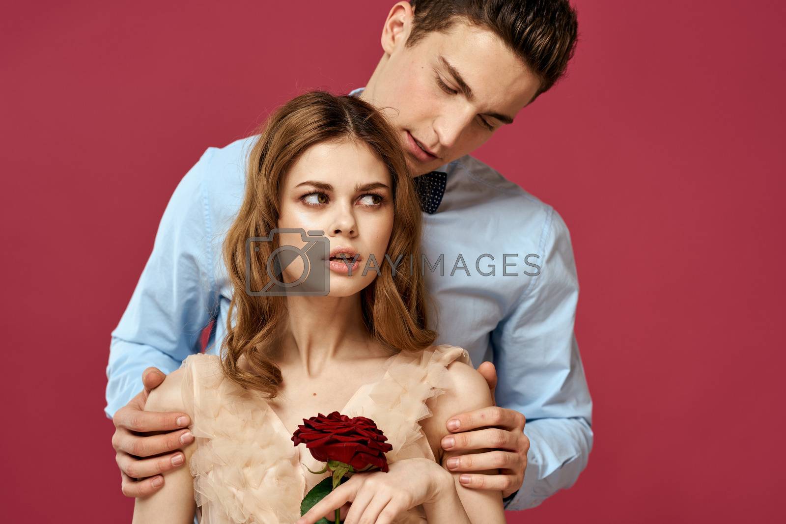 Lovers people with rose in hands on pink isolated background hug emotions happiness romance feelings. High quality photo