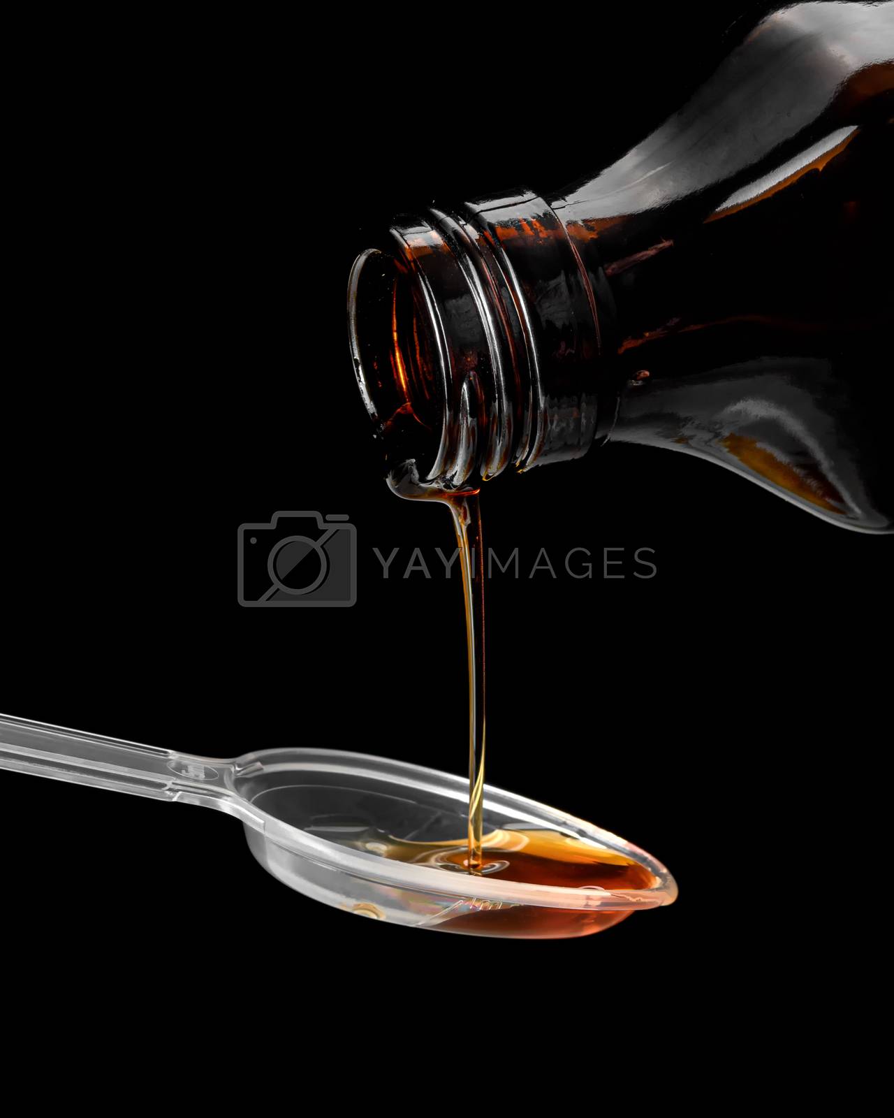 Royalty free image of Syrup is poured into a spoon, close - up on a black background by VladimirZubkov