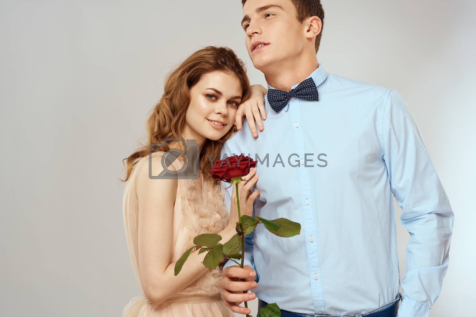A loving young couple with a red rose in their hands on a light background romance. High quality photo
