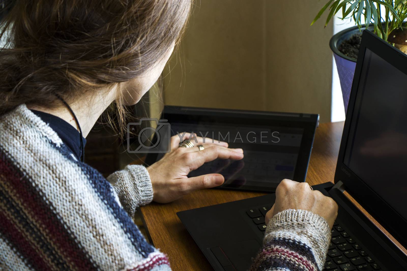Royalty free image of Woman working with notebook in workplace, digital tablet, mobile phone, coffee and plants by Taidundua