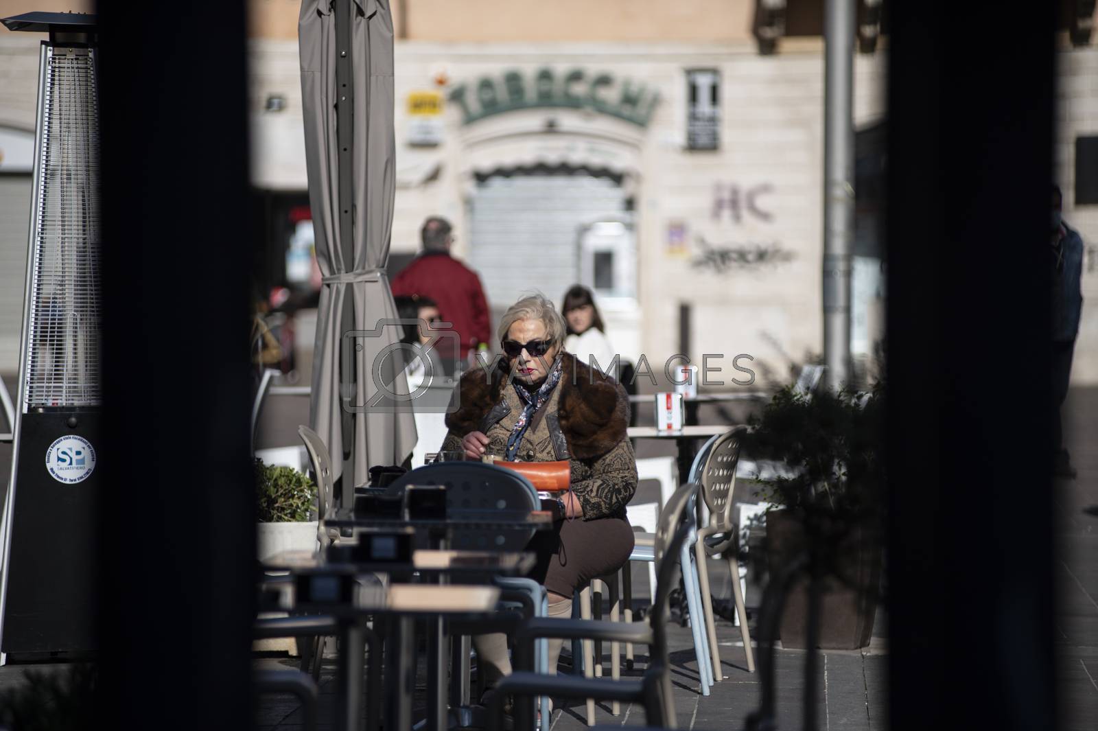 Royalty free image of woman sitting at a table in an outdoor cafe by carfedeph
