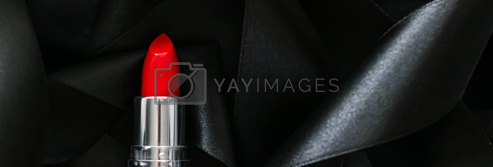 Royalty free image of Red lipstick on black silk background, luxury make-up and beauty by Anneleven