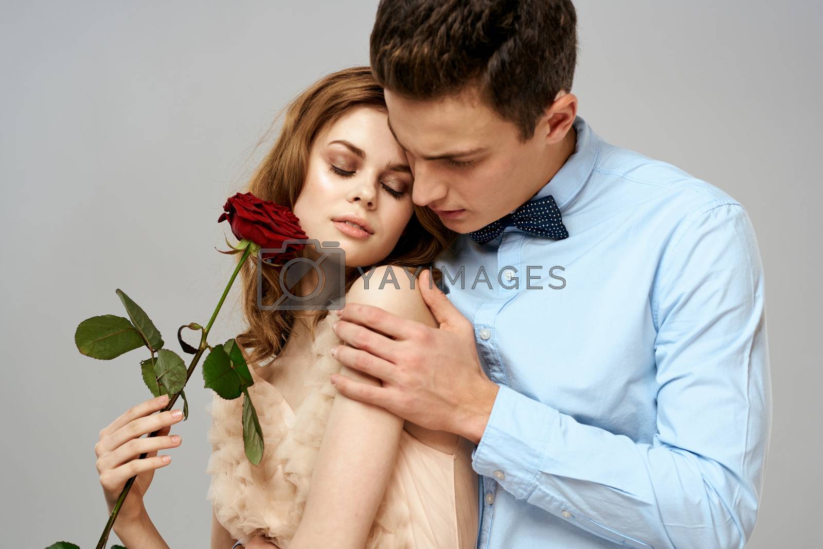 Cheerful young couple romance embrace relationship red rose lifestyle light background. High quality photo